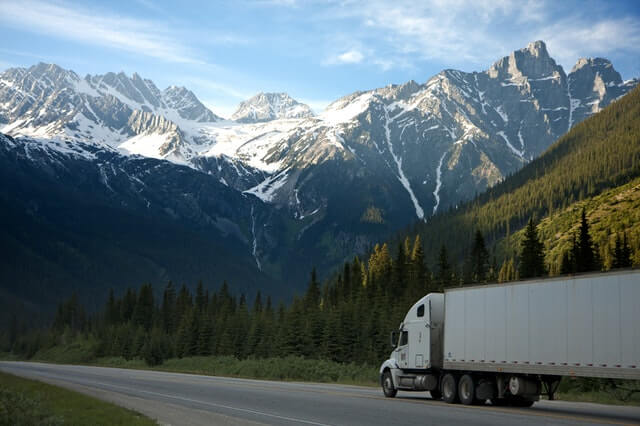 Semi tractor trailer in front of mountains